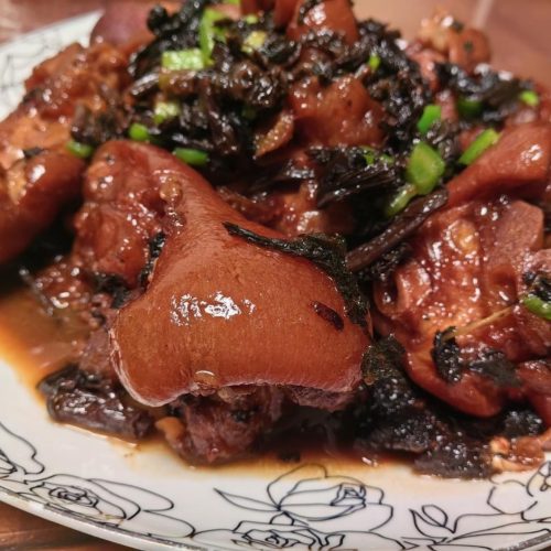 Braised pork trotters with preserved mustard greens served in a dark bowl