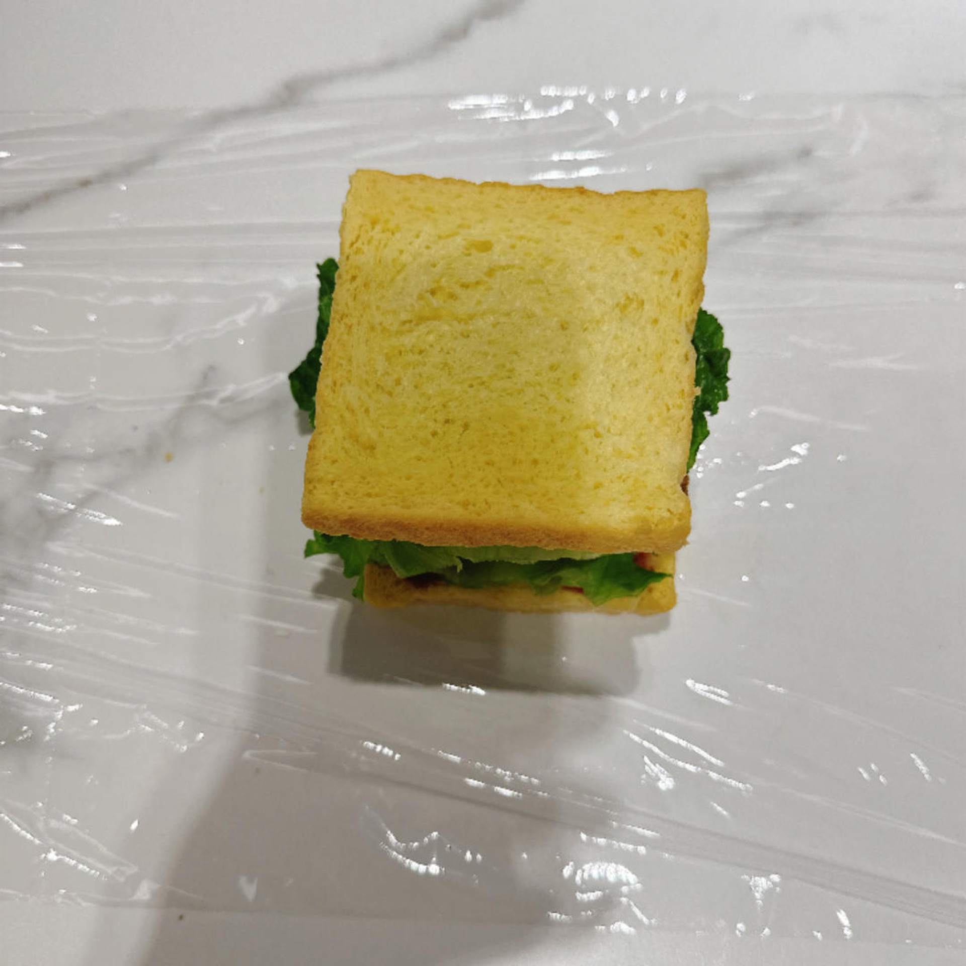 Pull out a longer sheet of plastic wrap to wrap the sandwich.