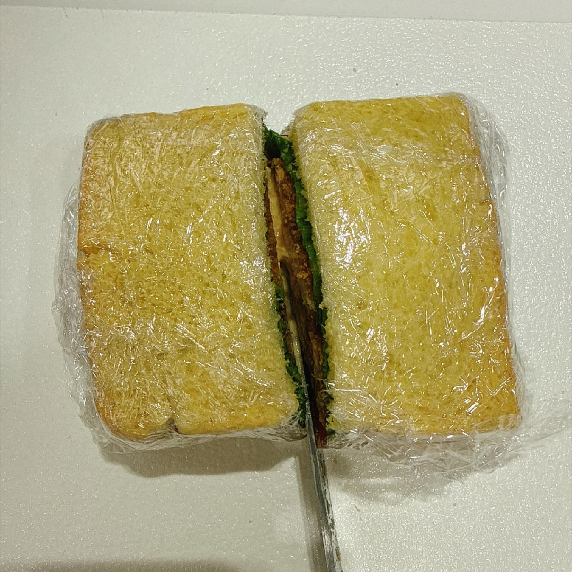 Cut the wrapped sandwich in half.