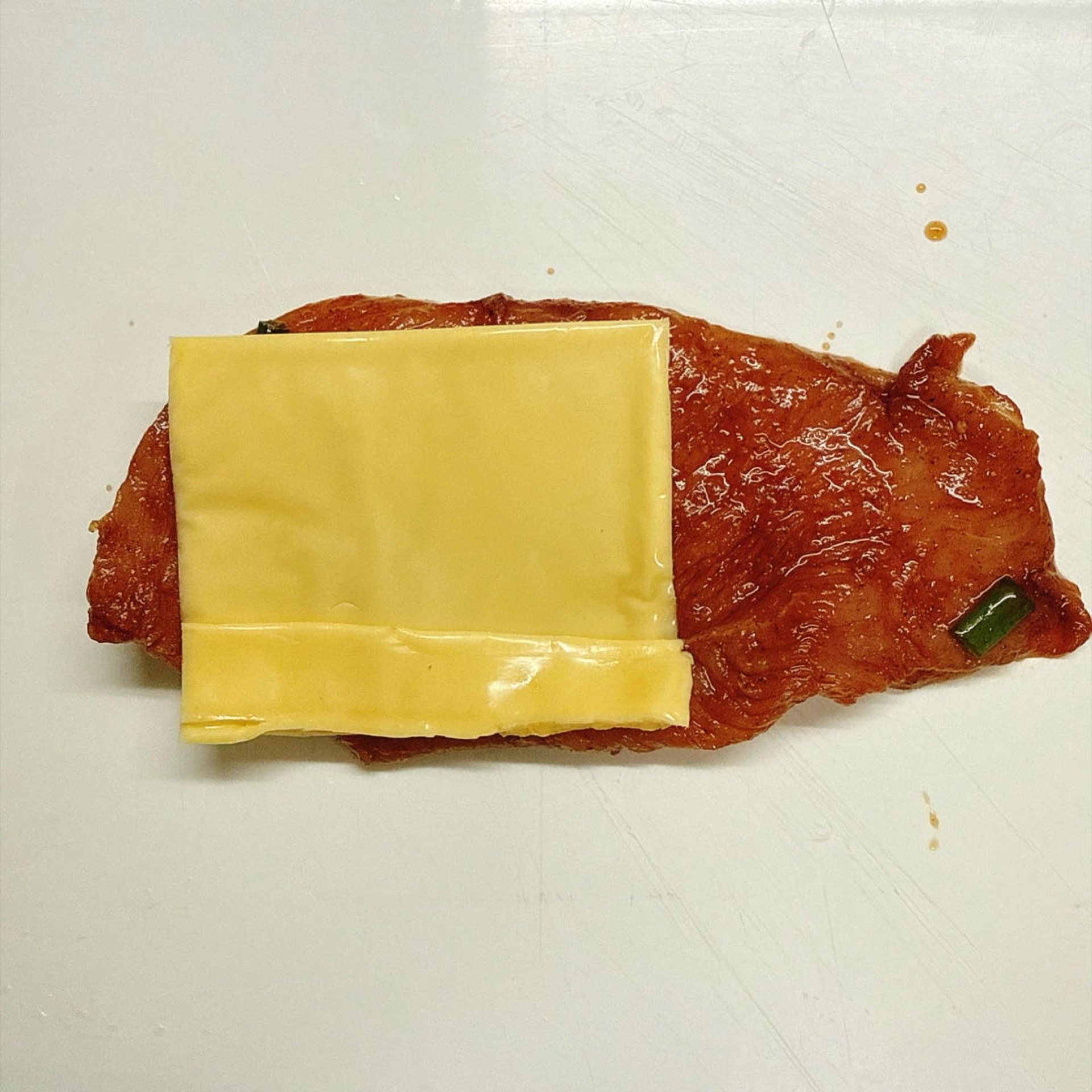 Open up each marinated chicken breast and place a folded slice of cheese inside.