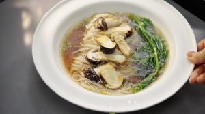Pan-fry a few mushrooms as a topping, season the bottom of a bowl with scallion and salt, pour in the hot chicken broth, and cook some noodles in a separate pot — that's your broth