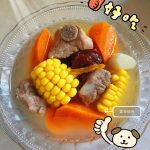 A bowl of pork rib soup with corn and yam, milky broth with corn rounds and carrot