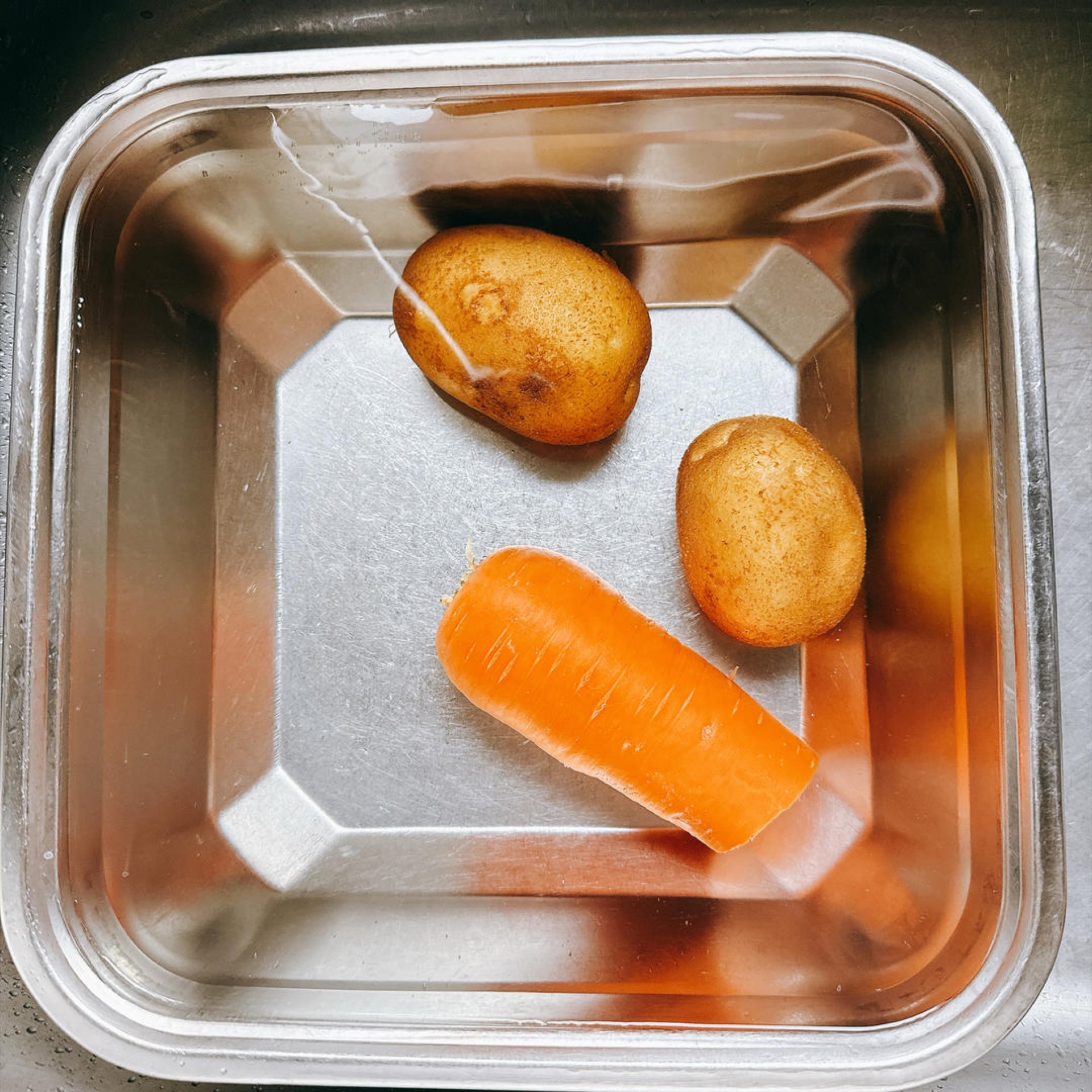 Peel 2 small potatoes and half a carrot and set them on the cutting board.