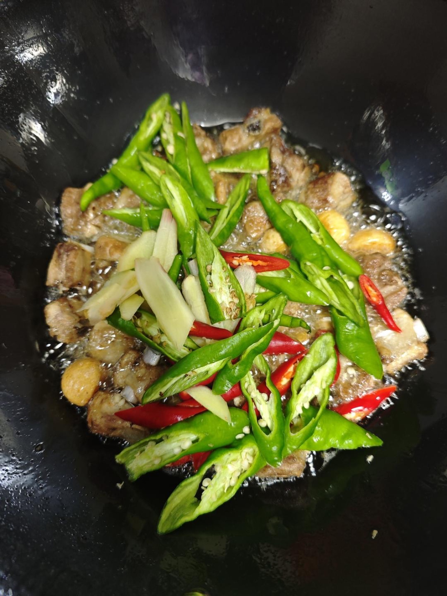 Add the ginger and the green and red chilies and stir-fry until the chili heat blooms.