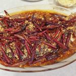 Garlic blast fish on a white plate topped with garlic sauce and sizzling chili oil