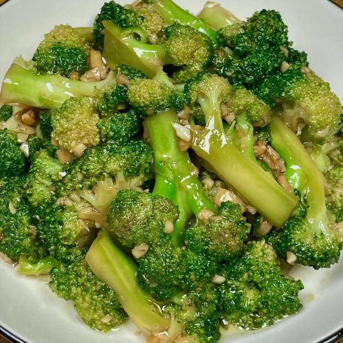 Garlic oyster sauce broccoli on a white plate, glossy green florets coated in savory sauce