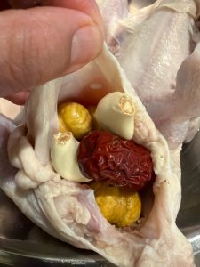 Pack the soaked rice, jujubes, garlic and chestnuts into the chicken's cavity, using as much as you like.