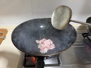 Heat 30 g of rapeseed oil in a wok and add the pork belly, frying slowly until it renders and turns crisp and golden at the edges.