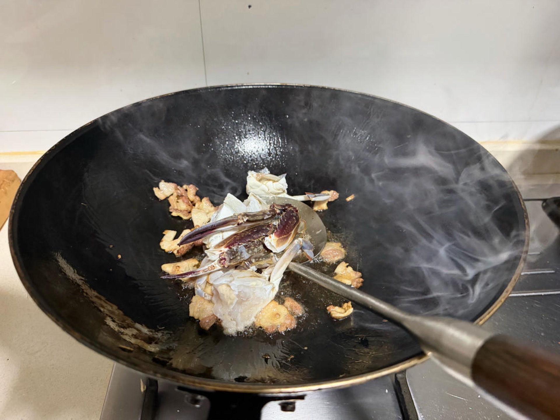 Add the chopped swimming crab and do not stir — let the pieces sear and set in place. Once set, add the garlic, ginger and shallots and fry briefly until fragrant.