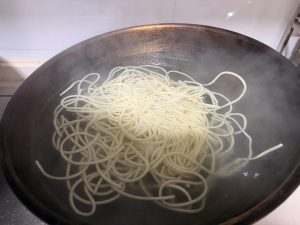 While the topping cooks, bring a second pot of water to a boil and add the alkaline noodles. This step must run at the same time as the previous one, seamlessly.