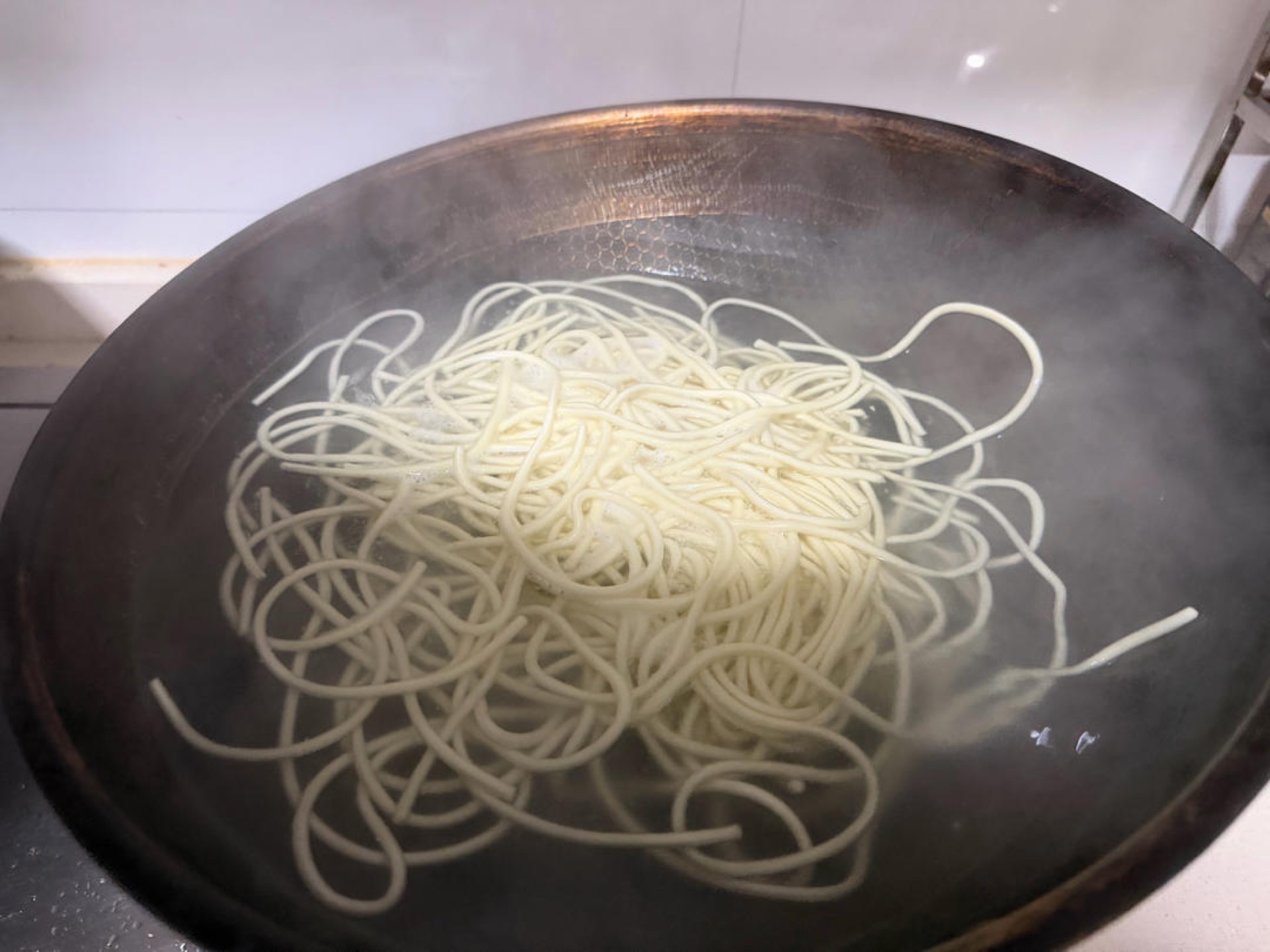 While the topping cooks, bring a second pot of water to a boil and add the alkaline noodles. This step must run at the same time as the previous one, seamlessly.