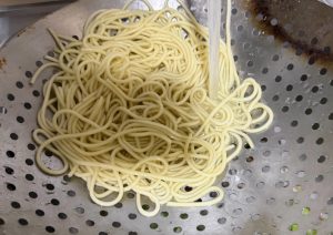 When the water comes back to a boil, scoop the noodles out and rinse them under cold water.