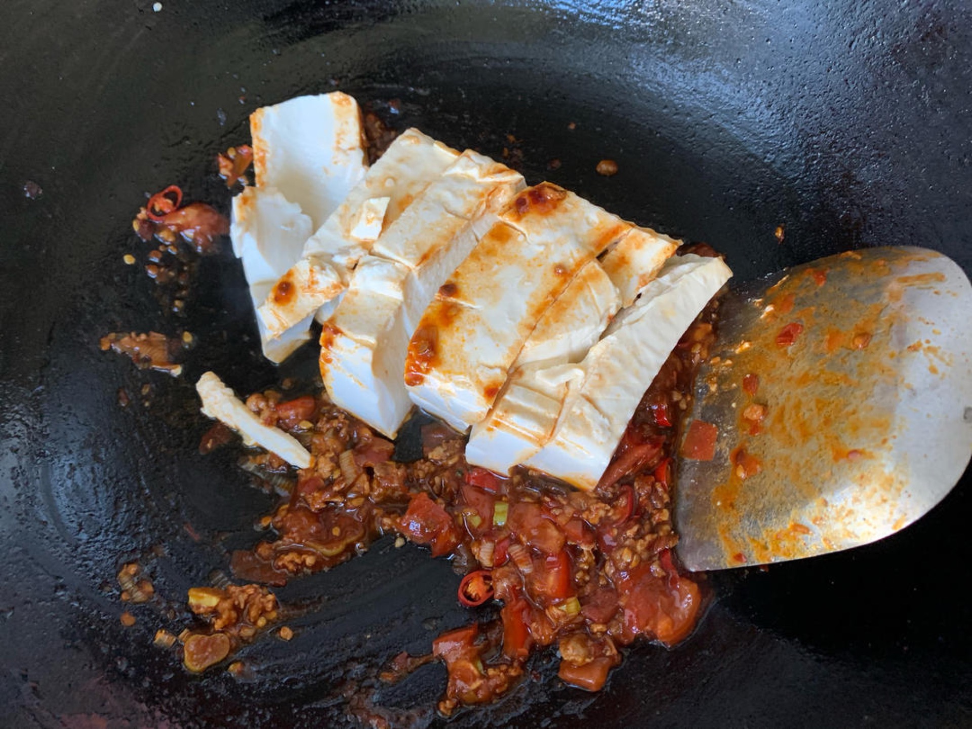 Slide in the tofu and break it into small pieces with the spatula, then stir gently until the tofu is evenly coated in the sauce.