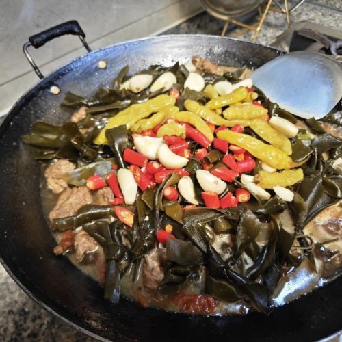 Jiangxi braised duck with kelp in a dark glossy sauce, garnished with fresh herbs