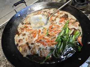Pour in the bottle of beer, or 2/3 cup of rice wine if you have it — rice wine braises more fragrantly, but beer works if not — add the dried chilies and lemongrass, and simmer for