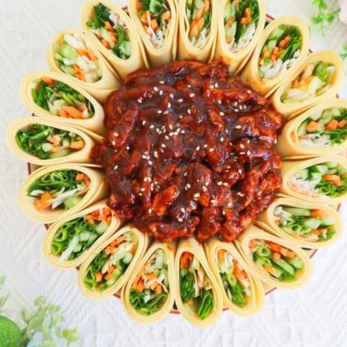 Shredded pork in sweet bean sauce served in the center of a plate ringed with tofu skin rolls