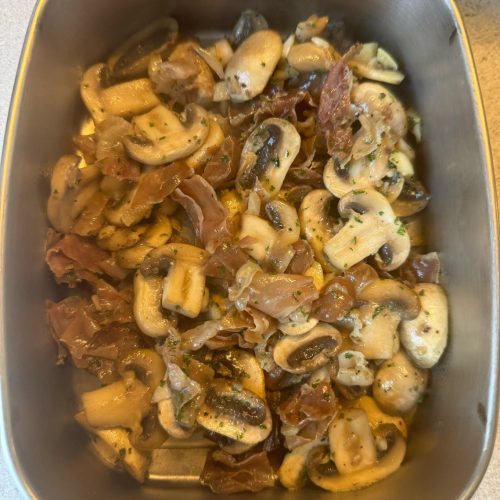 Stir-fried mushrooms with Parma ham and parsley in a black wok