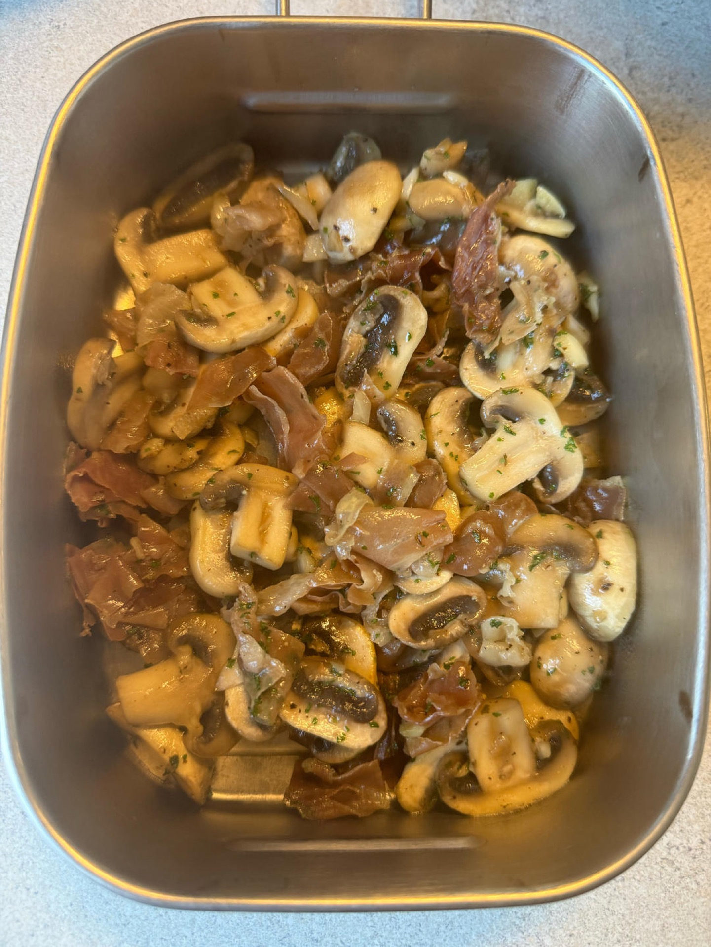 Stir-fried mushrooms with Parma ham and parsley in a black wok