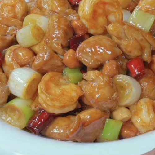 Kung Pao chicken with shrimp balls in a wok with peanuts and dried chilies