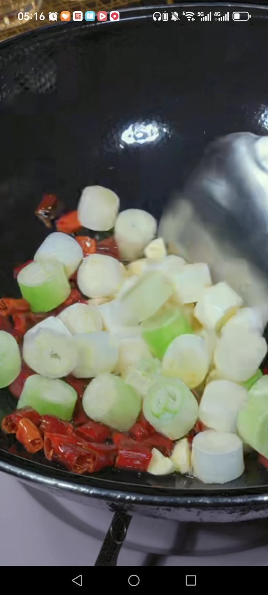 Add the last tablespoon of oil, then the scallion segments, sliced garlic, and dried chilies, and stir fry 30 seconds until fragrant and the chilies darken slightly.