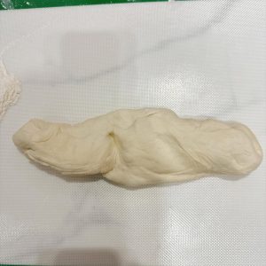 Dust the work surface with flour, press the dough to deflate it, and roll it into a long log.
