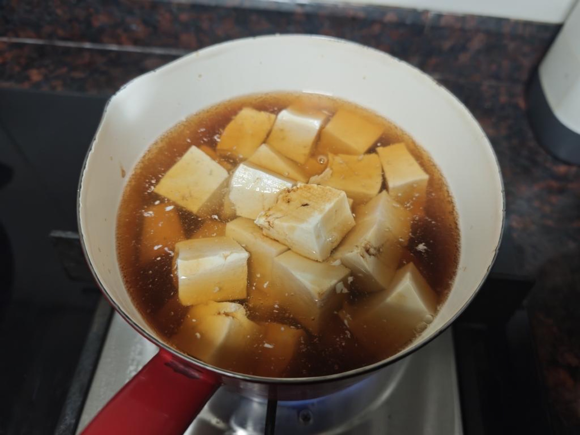 Bring the water and soy sauce to a gentle simmer, slide in the tofu cubes, and poach for 3 minutes, then drain carefully and set aside.