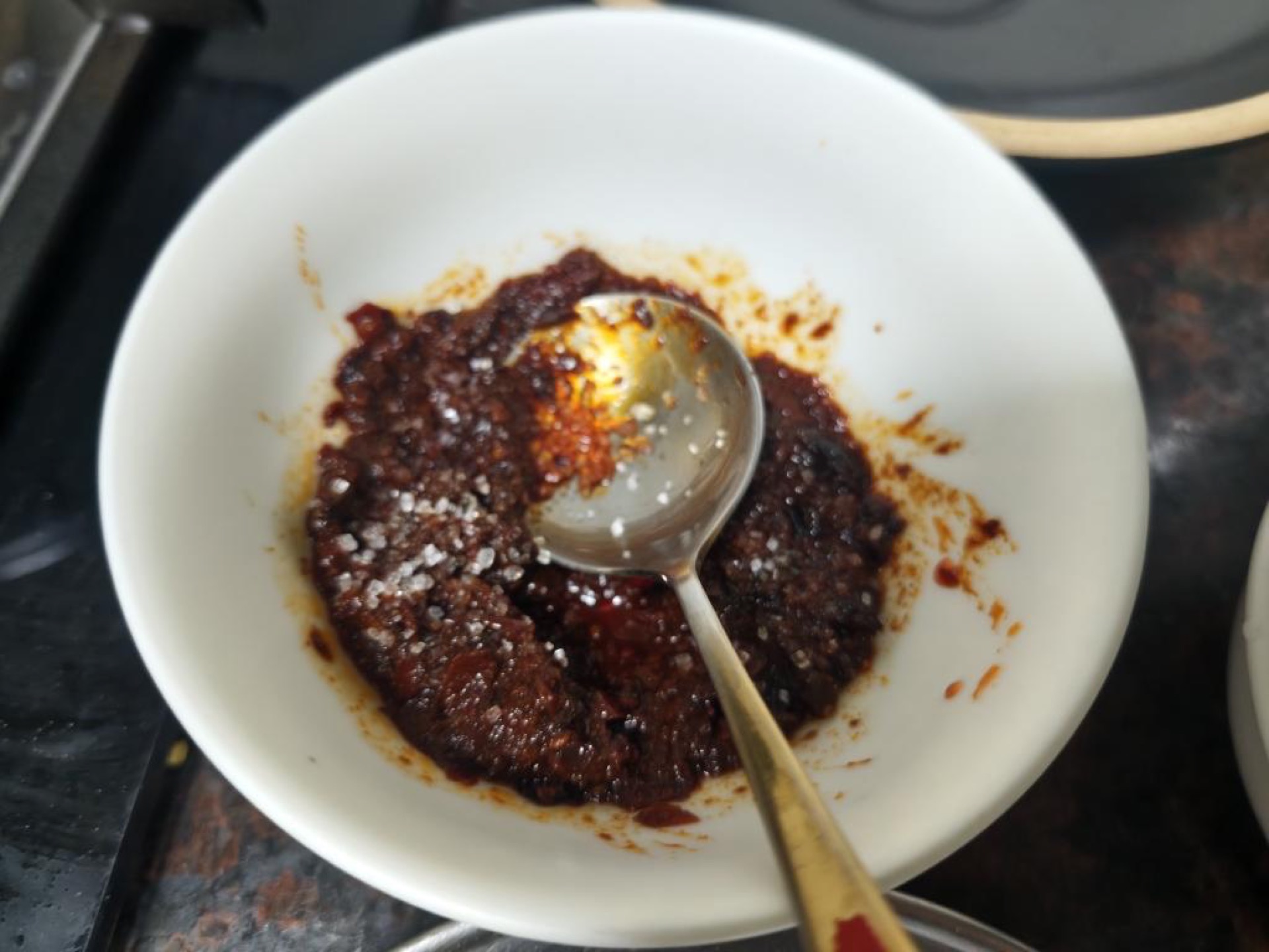 Mash the doubanjiang and fermented black beans together, fry them in the rendered beef fat until the oil turns red, then add the garlic, ground Sichuan peppercorn, and dried chili