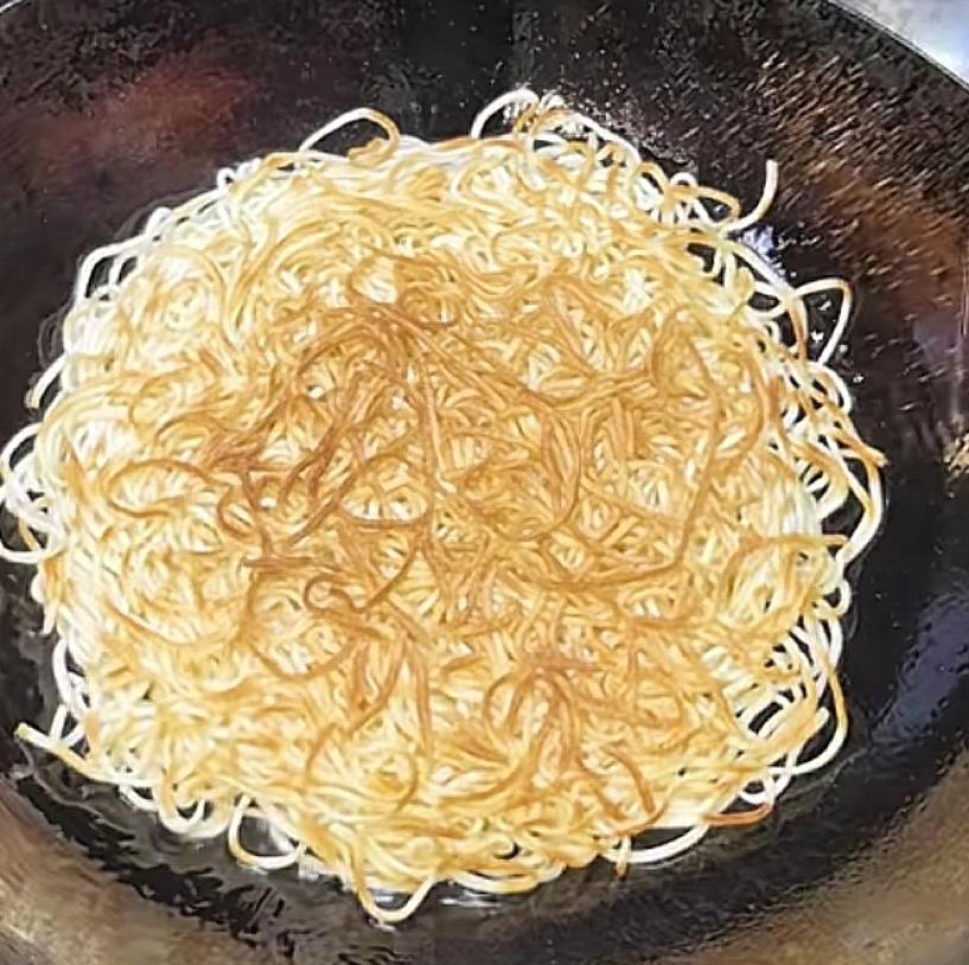 Heat a generous amount of oil in a wok, spread the fresh noodles flat in an even layer, drizzle oil around the edge of the wok, and pan-fry until both sides are golden brown, then