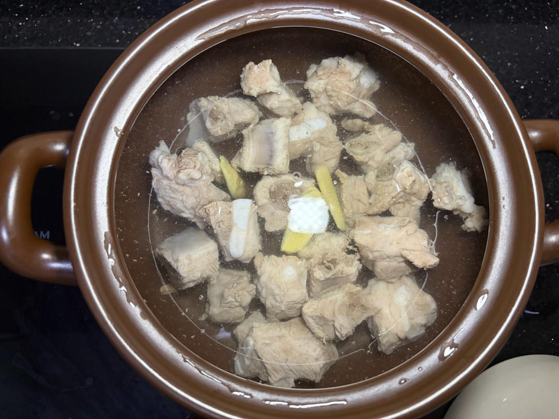 Add boiling water to a clay pot, add the ribs and ginger slices, cover, bring to a boil over high heat, then turn to low and simmer about 40 minutes — use the braising time to prep