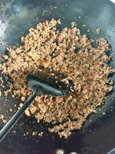 Heat the wok with cool oil, add the ground meat seasoned ahead with a little salt, and stir-fry until the fat renders, then add the fine chili powder, light soy sauce, and white pe