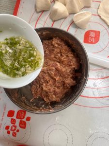 Add the scallion-ginger water to the ground pork in 3 additions, stirring clockwise until each addition is absorbed, then stir in the salt clockwise until the mixture becomes stick