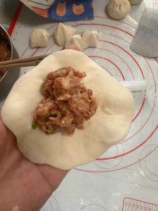 Knead the dough, cut it into portions, and wrap the filling into buns.