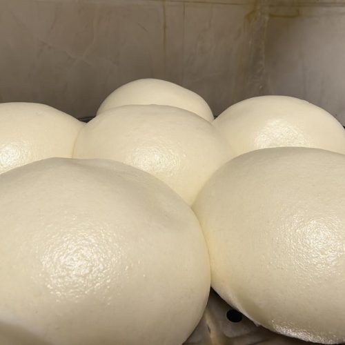 Silky steamed buns with a glossy glass-skin surface stacked in a bowl