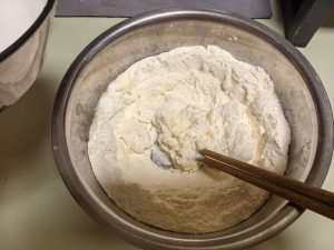 Pour the prepared water into the flour, stir in one direction until it forms shaggy flakes, then knead with your hands into a ball.