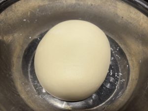 After half an hour, take the dough out; a few casual kneads will smooth it out, no long kneading needed. Put it back in the fridge and take it out the next day when you want to mak