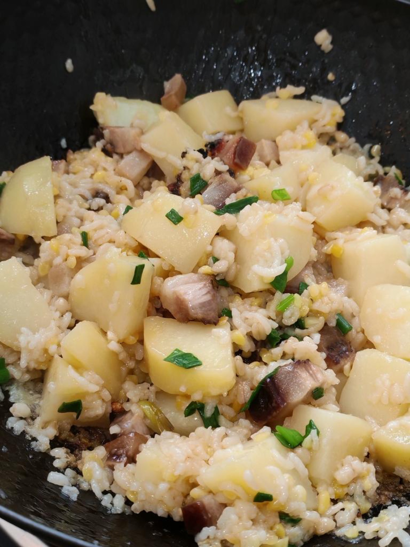 Soy sauce pork potato rice served in a wok with scallions on top
