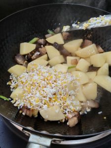 Heat the oil in a wok and stir-fry the pork and potato chunks together over medium heat until the pork releases its aroma and the potatoes are lightly coated.