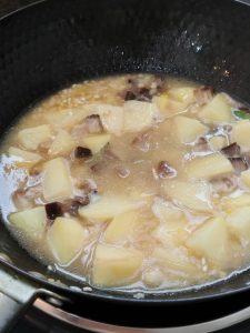 Add the soaked, drained rice and pour in water until it just covers the potatoes, then level the surface without stirring.