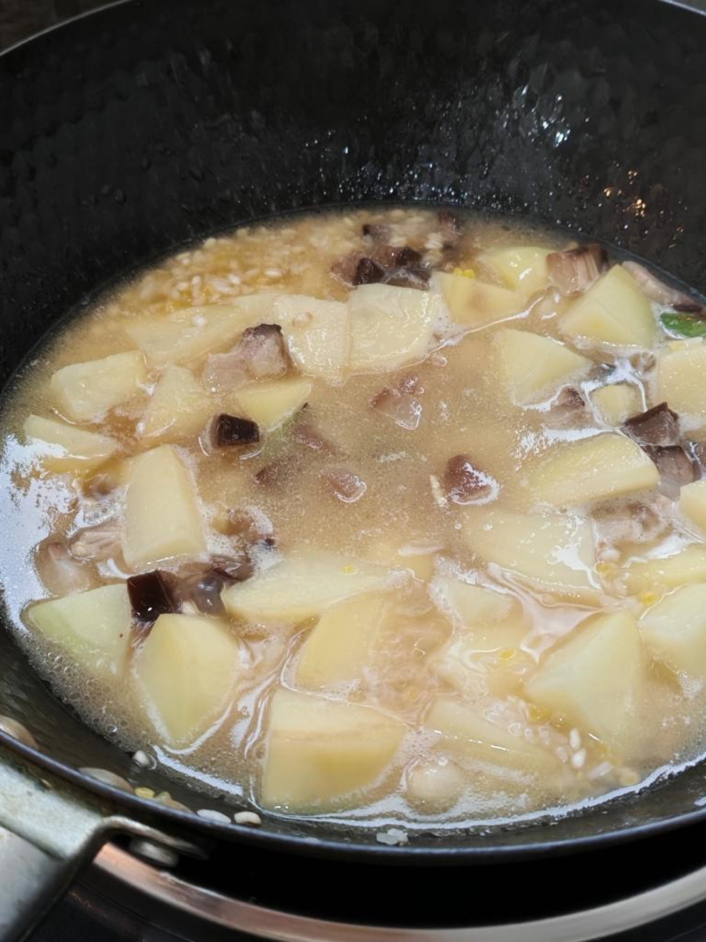 Add the soaked, drained rice and pour in water until it just covers the potatoes, then level the surface without stirring.