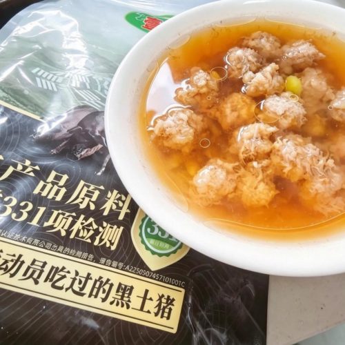 Steamed pork meatball soup with edamame served in a deep white bowl with clear broth