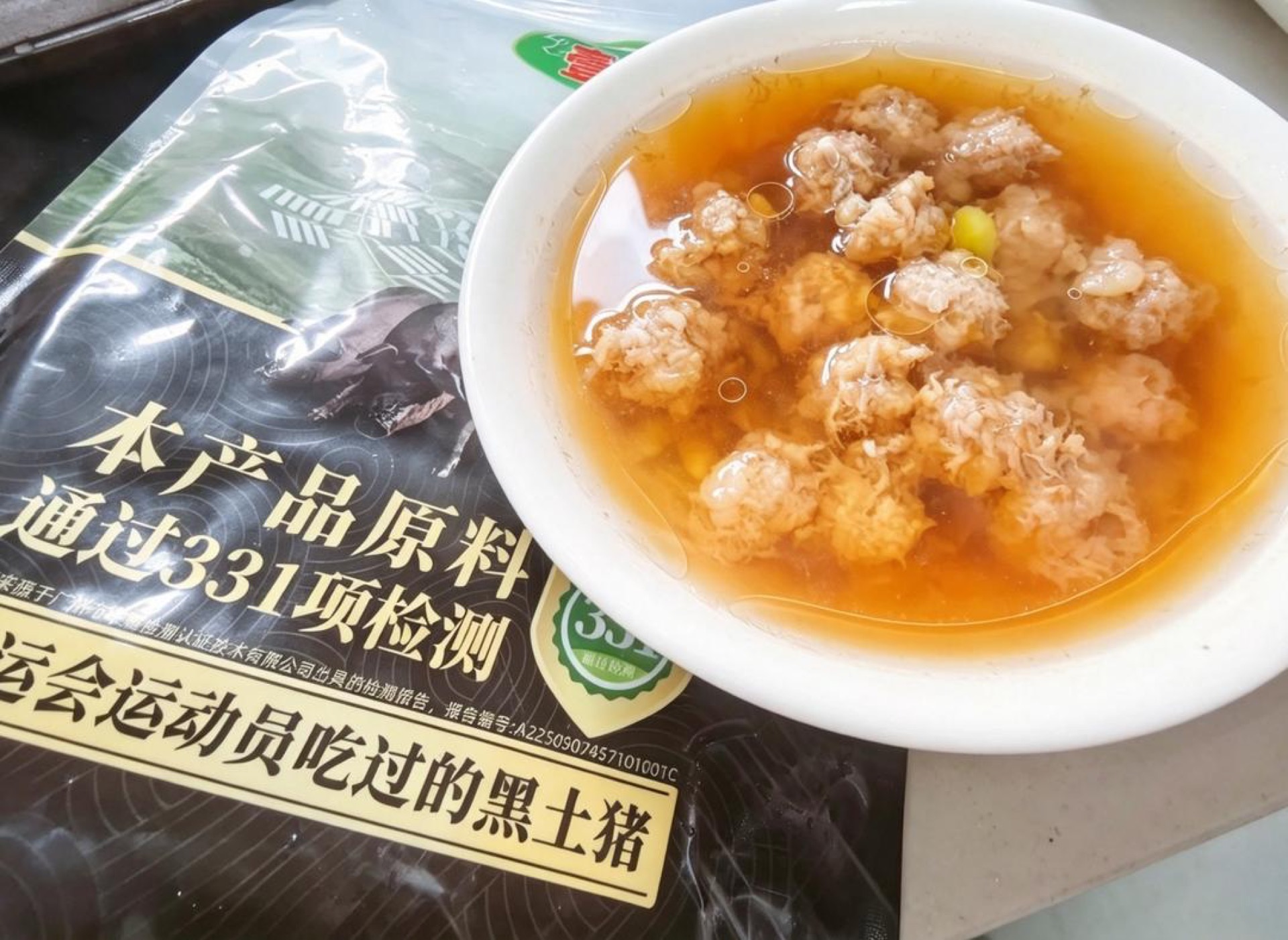Steamed pork meatball soup with edamame served in a deep white bowl with clear broth