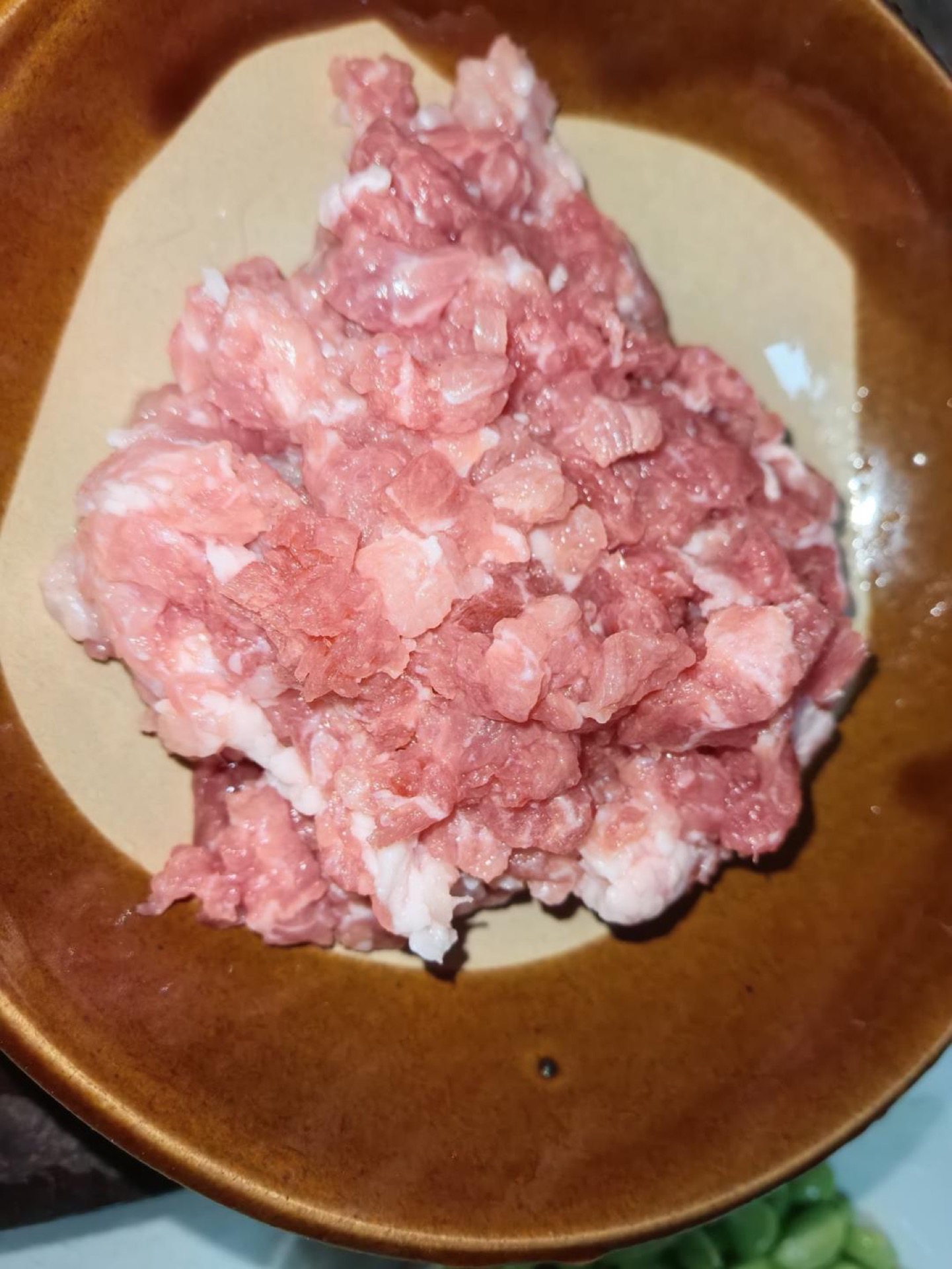 Chop the black pork into a fine mince, then add the salt, light soy sauce, white pepper, and cornstarch and stir in one direction until the mixture turns sticky, then let it marina