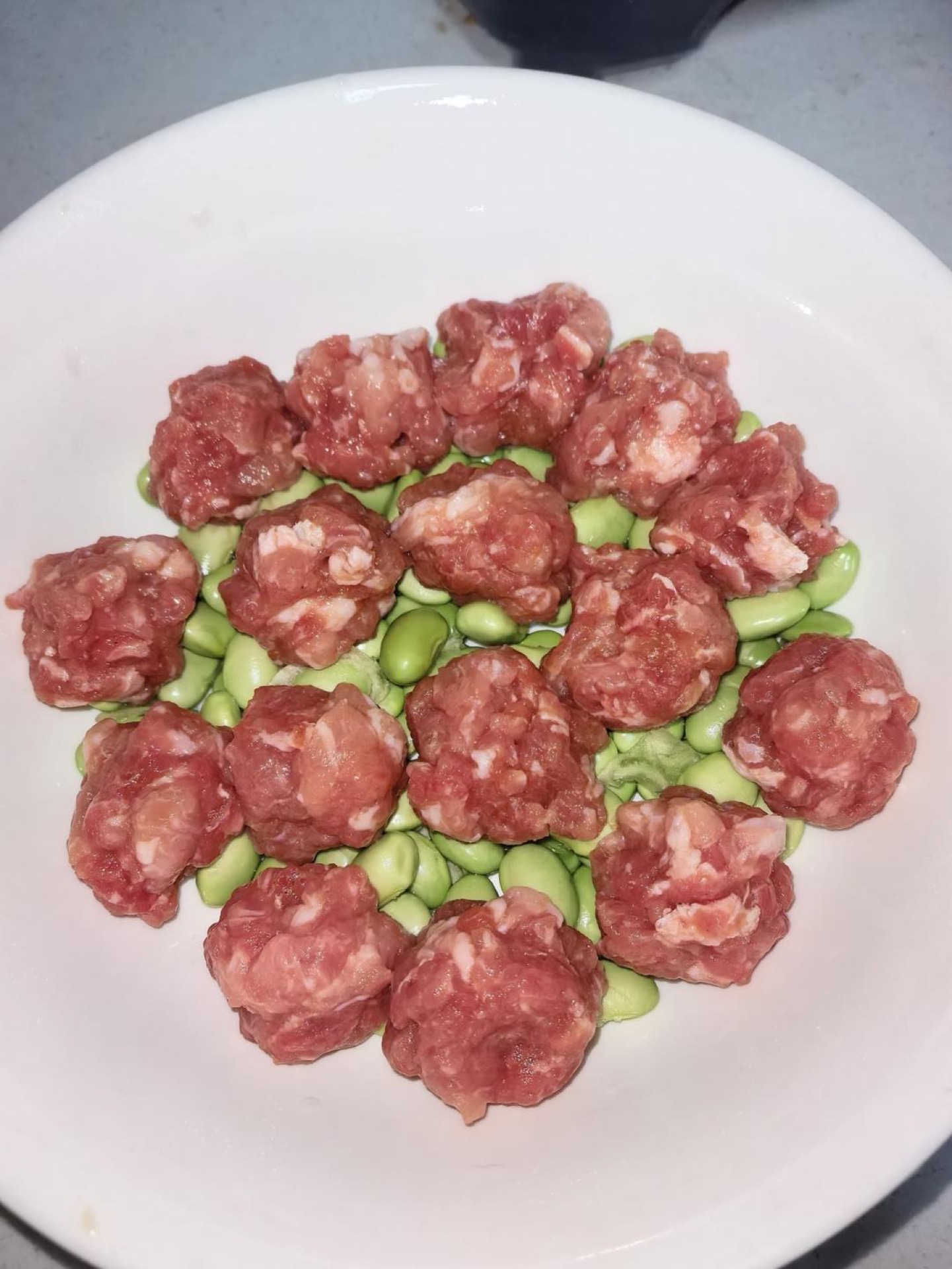 Roll the marinated pork into evenly sized meatballs, about 1 inch across, and lay them in a single layer on top of the edamame.