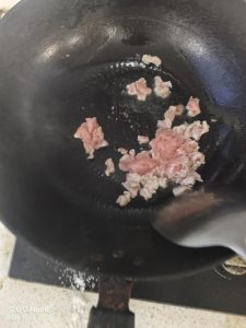 Heat a small amount of oil in the wok and slide the pork pieces apart, stir-frying until the color turns white.