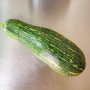 A farm-grown young pumpkin, small and tender, with pale green skin and soft seeds that scoop out easily.