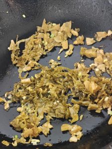 Leave the base oil in the wok, add the minced ginger and garlic to bloom, then tip in the prepared pickled cabbage; stir over high heat to drive off its moisture and release that s