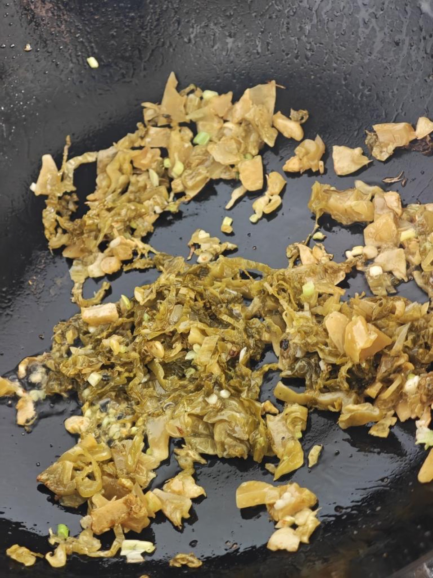 Leave the base oil in the wok, add the minced ginger and garlic to bloom, then tip in the prepared pickled cabbage; stir over high heat to drive off its moisture and release that s