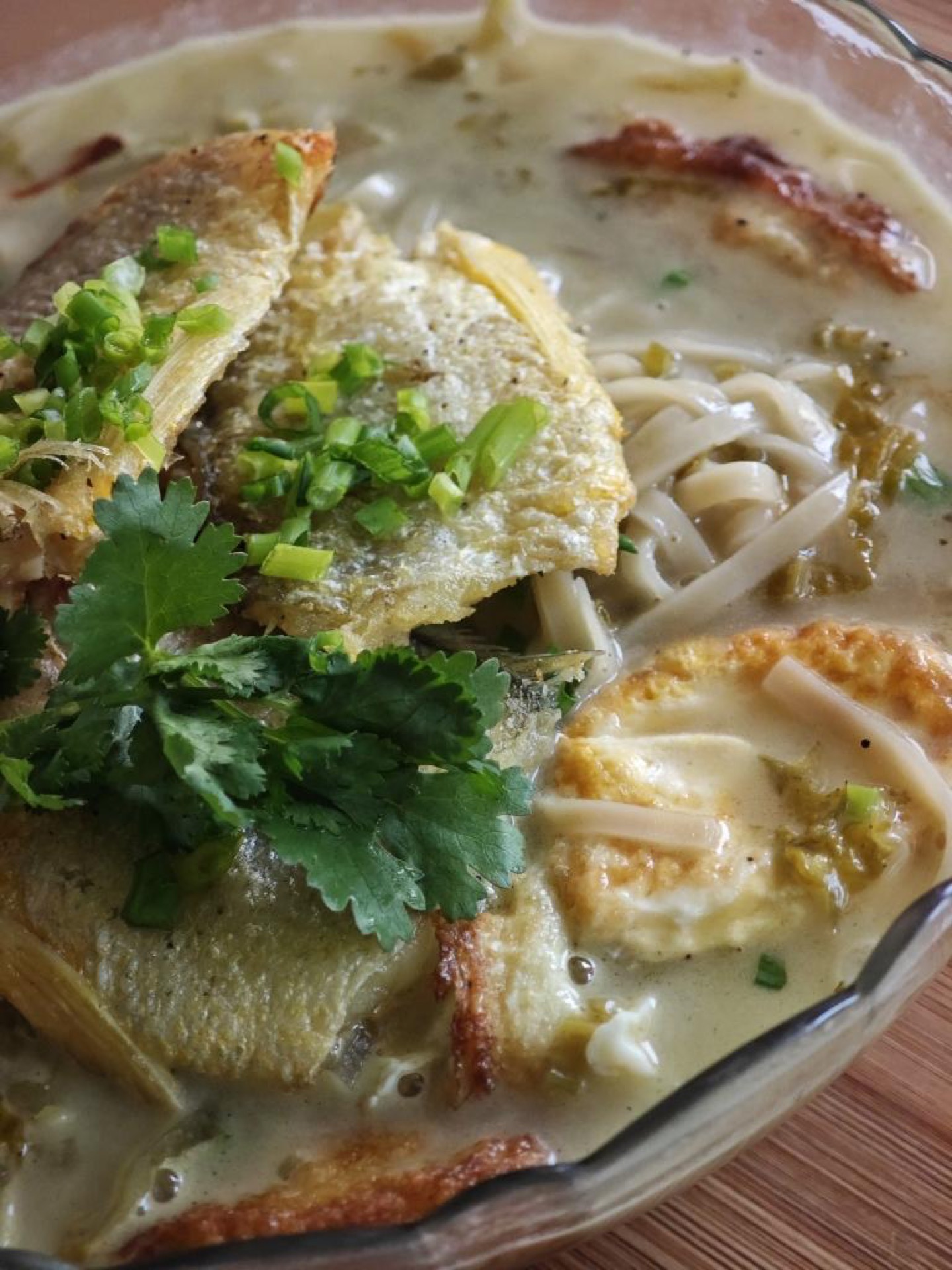 Pour the noodles and broth into a large bowl, arrange the reserved fish fillets on top, and finish with bright green scallion and cilantro.