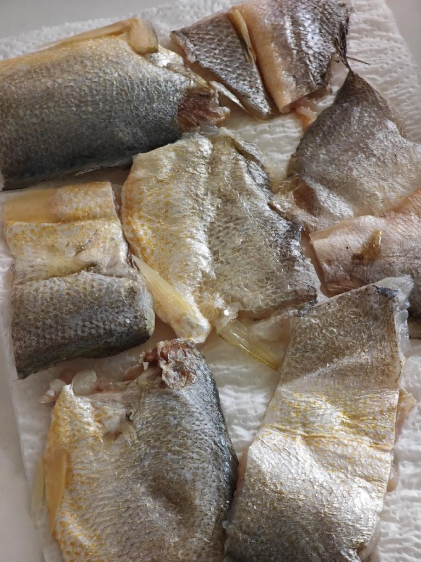 After the yellow croaker fillets thaw, pat them completely dry with paper towels; this is the key to pan-frying fish without tearing the skin.