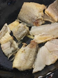 Heat the wok, add cool oil, sprinkle in a little salt to prevent sticking, and lay the fish pieces in to fry over medium-low heat.